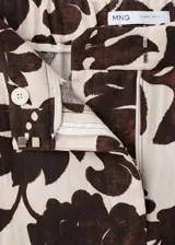 Pantalón largo de corte recto y tejido fluido, con diseño estampado floral en tonos marrón y crudo, bolsillos laterales y cierre oculto.