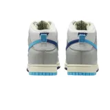 Championes Nike Dunk High Retro SE de corte alto, con diseño en paneles de cuero blanco y gris. Presenta un swoosh lateral dividido en dos tonos de azul, suela intermedia con acabado envejecido y suela exterior bicolor en azul claro y oscuro.