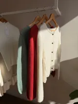 Saco tejido de punto liviano, color verde menta, con cuello redondo, cierre frontal de botones oscuros y diseño de corte corto.
