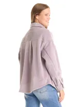 Sobrecamisa de pana con textura acanalada, corte oversize y silueta holgada. Presenta cuello clásico, cierre frontal con botones metálicos, mangas largas con puños abotonados y dos bolsillos frontales tipo parche con solapa.