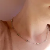 Collar plateado fino con cadena de eslabones y pequeñas bolitas distribuidas a lo largo de la cadena.