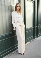 Pantalón recto de tiro medio color beige, con bolsillos laterales y un cinturón incorporado con detalle de flecos en los extremos.