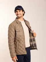 Campera acolchada azul marino con cuello de pana, cierre frontal con cremallera y bolsillos con solapa en el pecho.