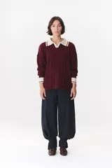 Sweater de punto color marrón con cuello polo en contraste color crema. Presenta diseño de rayas verticales texturizadas, mangas largas con puños en color crema y corte holgado.