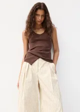 Pantalón de vestir de tiro medio con diseño de rayas verticales en tono beige y crudo. Presenta pernera recta y holgada, con pinzas delanteras y bolsillos laterales.