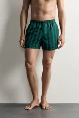 Short de baño confeccionado en tejido técnico, con diseño de rayas verticales en color verde y negro. Cuenta con cintura elástica ajustable con cordón, bolsillos laterales y bolsillo trasero con vivo, además de forro interior.