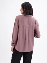 Camisa de manga larga color malva, con cuello clásico, cierre frontal con botones y detalles de vivos negros en los puños.