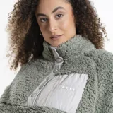 Campera de polar tipo sherpa color verde, con cuello alto y cierre frontal parcial con botones a presión. Presenta un bolsillo frontal con cierre y detalle de marca Reef.