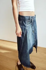 Falda midi de denim azul con tiro medio, diseño asimétrico de bajo cruzado y cinco bolsillos clásicos.