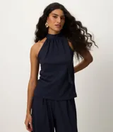 Blusa azul marino sin mangas con cuello alto y detalle de lazo integrado. Confeccionada en mezcla de poliéster, viscosa y elastano, de corte recto.