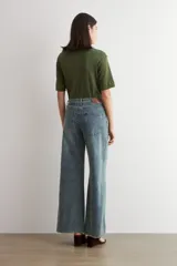 Pantalón de jean estilo wide leg con tiro medio, corte holgado y ruedo deshilachado.