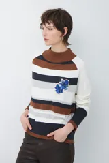 Polera de tejido de punto con diseño de rayas horizontales en tonos beige, marrón, gris y negro. Presenta cuello redondo y mangas largas con puños en contraste.