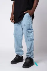 Pantalón tipo cargo confeccionado en denim de lavado claro, con bolsillos laterales con solapa y bolsillos frontales tipo parche. Presenta un corte holgado y puños elásticos en los tobillos.