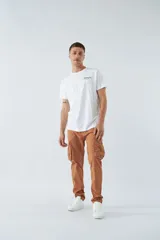 Pantalón cargo color beige, corte slim, con cierre y botón en la cintura, pasacintos, bolsillos cargo con botones y sin puños.