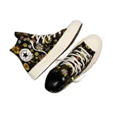 Championes Converse modelo Chuck 70 de caña alta, con diseño estampado de flores en tonos amarillos, rosas y verdes sobre base negra. Presenta el parche clásico de la marca en el lateral, puntera de goma y suela de plataforma en color crema.