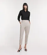 Pantalón de vestir color beige claro, estilo carrot con cintura ancha y tiro alto. El largo es tobillero con puños doblados.