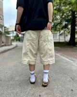 Bermuda de corte baggy color beige crema, con costura vertical trasera en cada pierna y detalle artesanal visible en el bajo. Incluye un cordón extra confeccionado en la misma tela.