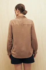 Camisa color café con textura sutil, cuello clásico, botones forrados a tono y mangas largas con puños fruncidos.