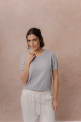 Remera tejida de punto fino en color negro, de manga corta, con escote redondo y terminaciones en rib en el cuello, mangas y ruedo.
