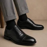 Zapato tipo Oxford de ecocuero negro con puntera reforzada, cordones al tono y suela de goma antideslizante.