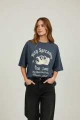 Remera de algodón de manga corta y cuello redondo, con diseño holgado y estampado gráfico frontal con motivos florales y tipografía vintage.