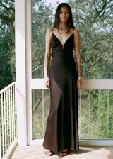 Vestido largo de satén color marrón chocolate, con tirantes finos, escote en pico profundo con detalle fruncido central y diseño recto.