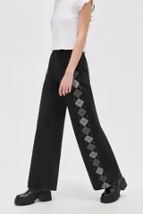 Pantalón de jean negro de tiro alto y corte ancho, con diseño de rombos geométricos grises a lo largo de los laterales.