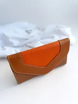 Billetera de cuero color naranja y marrón con cierre de broche y monedero externo.