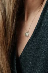 Collar de hilo encerado con un elegante colgante redondo de metal dorado con relieve del escudo de Uruguay.