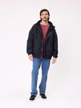 Campera reversible con capucha oculta, confeccionada en sarga de algodón con elastano en el exterior y nylon de poliéster en el interior. Presenta cierre frontal con botones a presión, costuras visibles en contraste y puños elásticos.