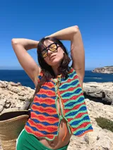 Chaleco tejido a mano en crochet con hilado 100% algodón, con diseño de ondas horizontales en colores azul, rojo y verde. Tiene tiras para atar en el frente.