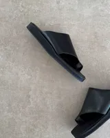 Sandalias negras de cuero vacuno con tira ancha sobre el empeine y espacio para el dedo gordo.