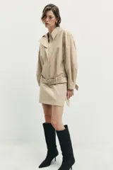 Vestido corto de cuello solapa y manga larga, con bolsillos delanteros y detalle de cinturón a tono. Presenta cierre frontal con cremallera oculta y bajo con aberturas laterales.