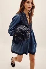 Vestido corto de tencel en color azul, con mangas largas abullonadas y escote en V profundo. Cuenta con detalles de bordados oscuros en el pecho, los puños y el ruedo, y una falda de corte evasé.