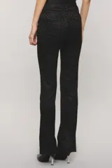 Pantalón sastrero negro con lúrex, de calce slim, botamanga flare y bolsillos ojal en la espalda. Presenta cierre frontal con broche personalizado y botón auxiliar interno.
