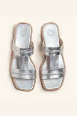 Sandalia plana de cuero color marrón, con tiras anchas y costuras blancas a la vista. Tiene punta cuadrada y un pequeño taco de 2 cm.