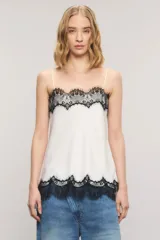 Top de satén blanco de corte regular, con breteles finos regulables y detalles de encaje negro estilo chantilly en el escote y el ruedo.