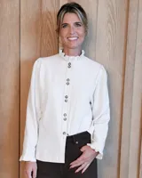 Camisa de manga larga con estampado de rayas verticales en tonos blanco y lila. Presenta cuello alto con volados, cierre frontal con doble botonadura y puños con volados.