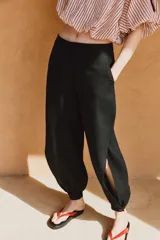 Pantalón bombacho de tiro medio confeccionado en lino, color negro, con pernera abullonada y bajo acabado en puño con botón.