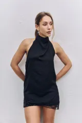 Top negro de cuello halter con acabado satinado y detalle de encaje con lentejuelas en el ruedo.