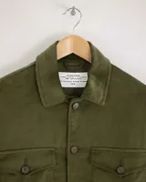 Camisa de pana color beige, de manga larga, con cuello camisero, cierre frontal de botones y dos bolsillos de parche con solapa en el pecho. Presenta un corte recto y holgado.