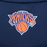 Musculosa de básquet azul marino con detalles laterales en naranja. Presenta el logo oficial de los New York Knicks estampado en el frente y etiqueta de autenticidad NBA en el ruedo.