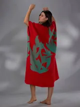 Capullo o kimono de paño 100% algodón, color rojo con estampado exclusivo en tono verde, de morfología amplia y envolvente, con bolsillos laterales y cinto independiente para ajustar la cintura.