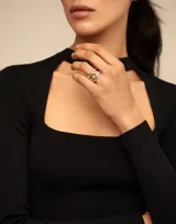 Anillo de metal bañado en plata con diseño curvilíneo de estilo oriental y logo de la marca grabado.