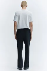 Pantalón sastrero negro de corte slim fit, con presillas para cinto, bolsillos laterales al bies y bolsillos traseros ojalados.