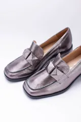 Mocasines plateados de cuero con aplique geométrico al tono y taco cuadrado.
