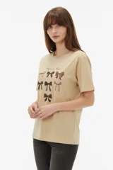 Remera de algodón blanca, de corte holgado, con cuello redondo y diseño estampado en el centro que incluye un gato comiendo de un plato y la inscripción 'Wild Cats'.