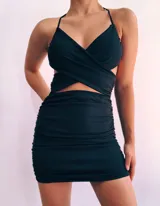 Minivestido fucsia con escote halter cruzado, espalda descubierta y falda ajustada con frunces.