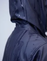 Gabardina impermeable azul marino, marca Weatherproof, con cierre central, bolsillos delanteros, capucha fija y forro interno.