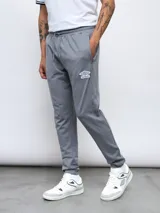 Pantalón de jogging gris de felpa sin friza, con cintura elástica ajustable con cordón y logo de Umbro estampado en blanco en el muslo izquierdo.